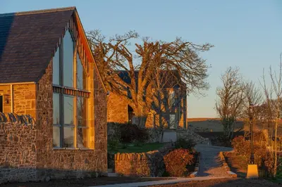 a brick house with large windows on the side of it at Falcon Steading in Buchanty