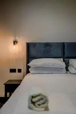 a white bed with a blue headboard and white pillows at The Righ in Oban