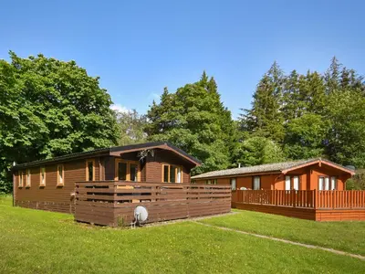 a log cabin in a yard next to a house at Lomond View Lodge in Rowardennan
