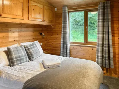 a bedroom with a bed in a wooden cabin at Lomond View Lodge in Rowardennan