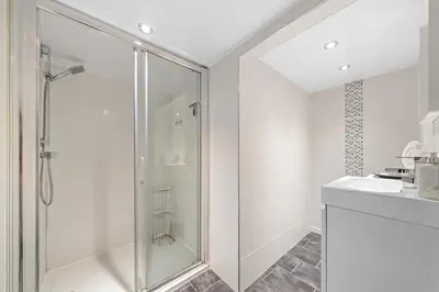 a white bathroom with a shower and a sink at Perfect location for beach and golfing in Troon