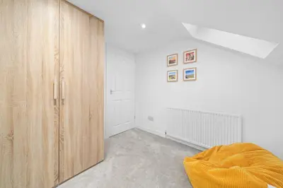 a bedroom with white walls and a wooden cabinet at Perfect location for beach and golfing in Troon