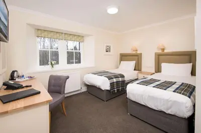 a hotel room with two beds and a desk at The Inveraray Inn, BW Signature Collection in Inveraray