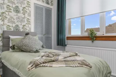 a bed with a blanket on it in a bedroom with windows at Royal Troon Golf Let in Troon