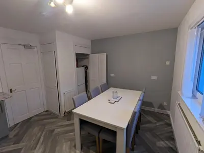 a room with a white table and chairs and a door at 4 bedroom Townhouse Greenock in Greenock