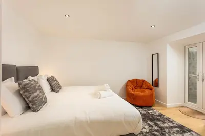 a white bedroom with a large bed and a chair at Wellington Lodge in Ayr