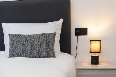 a bed with a black and white pillow and a lamp at Wellington Lodge in Ayr