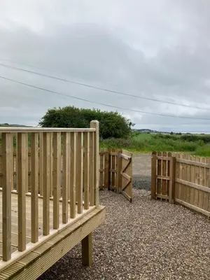 a wooden fence sitting next to a road at Wee Beach Hut Maidens in Maidens