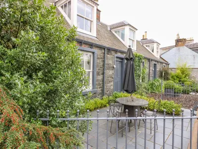 a patio with a table and an umbrella at Wee Cottage in Moffat
