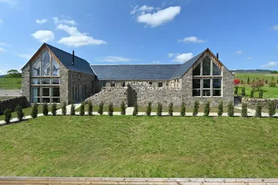a large stone house with a large yard at Merlin Steading with hot tub in Buchanty