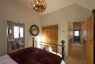 a bedroom with a bed and a chandelier at Merlin Steading with hot tub in Buchanty