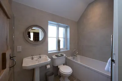 a bathroom with a sink and a toilet and a bath tub at Merlin Steading with hot tub in Buchanty