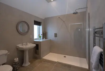 a bathroom with a shower and a toilet and a sink at Merlin Steading with hot tub in Buchanty