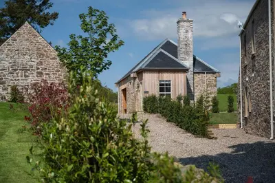 an old stone house with a chimney and a garden at The Bothy in Buchanty