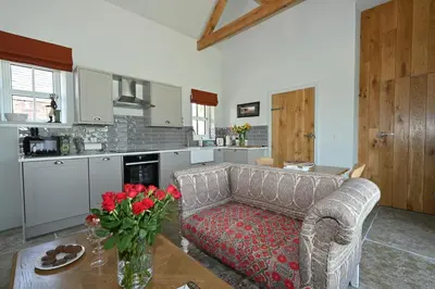 a living room with a couch and a table with roses at The Bothy in Buchanty