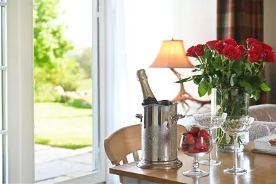 a table with a bottle of wine and a vase of roses at The Bothy in Buchanty