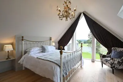 a bedroom with a bed and a chandelier and a window at Milton Farm in Buchanty