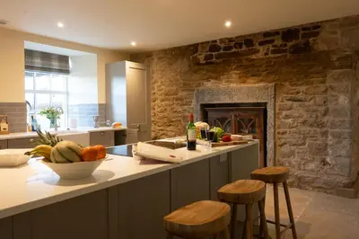 a kitchen with a counter with stools and a fireplace at Milton Farm in Buchanty