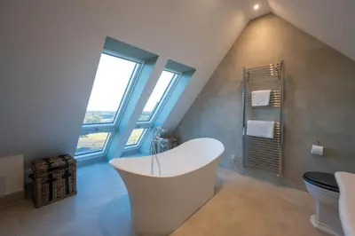 a bathroom with a white tub and a window at Milton Farm in Buchanty