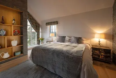 a bedroom with a large bed and a window at Milton Farm in Buchanty