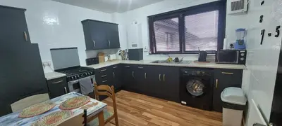 a kitchen with a washing machine and a table at Luxurious room with a private bathtub and shared toilet and kitchen 10mins from City Centre in Bailleston