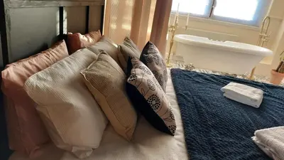 a group of pillows on a bed with a sink at Luxurious room with a private bathtub and shared toilet and kitchen 10mins from City Centre in Bailleston
