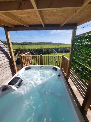 a hot tub on a deck with a view at The Galloway Steading -The Hedgehog's Hideout family cabin with Hot Tub and Fire Pit in Glenluce