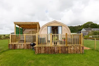 a small house with a deck on the grass at The Galloway Steading -The Hedgehog's Hideout family cabin with Hot Tub and Fire Pit in Glenluce