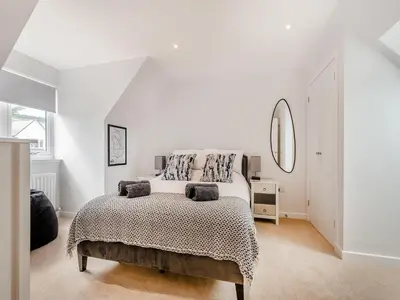 a white bedroom with a bed and a mirror at Riverbank in Lamlash
