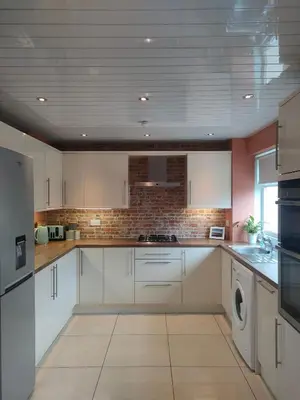 a kitchen with white cabinets and a washer and dryer at Troon Beach and Golf House in Barassie
