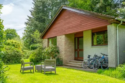 a house with two chairs and bikes parked next to it at Heatheryhaugh Lodges in Moffat