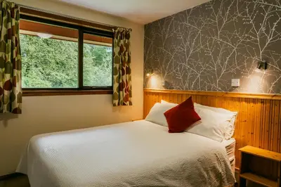 a bedroom with a white bed and a window at Heatheryhaugh Lodges in Moffat