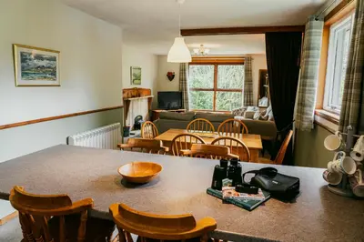a kitchen and living room with a table and chairs at Heatheryhaugh Lodges in Moffat
