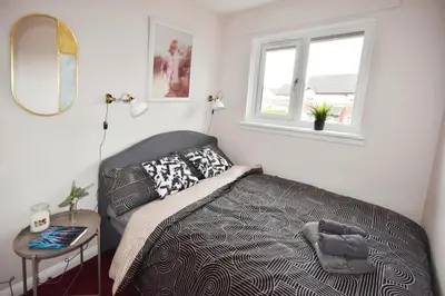 a small bedroom with a bed and a window at Beautiful house in Clydebank in Glasgow
