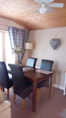 a dining room table with chairs and a ceiling fan at Baytree Lodge at three lochs holiday park, NEW ASK ABOUT OUR PACKAGES birthday ,anniversary,family,pamper packages available in Balminnoch