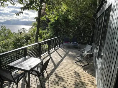 a deck with a table and chairs on a house at Cherrybrae Cottage in Saint Fillans