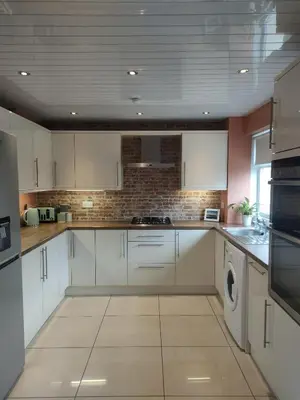 a kitchen with white cabinets and a washer and dryer at Troon Golf and Beach House in Troon