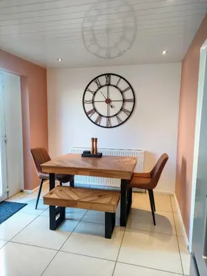 a dining room with a table and a clock on the wall at Troon Golf and Beach House in Troon