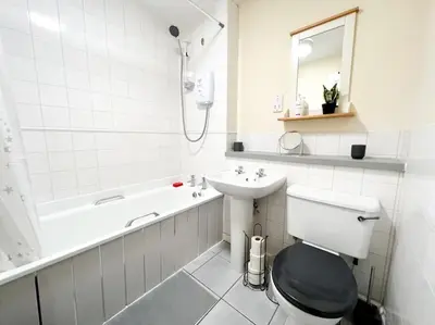 a white bathroom with a toilet and a sink at Cosy Riverside Home SECC Hydro in Glasgow