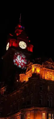 a large building with a clock tower at night at Haymaeket Centro Edinburgh in Edinburgh