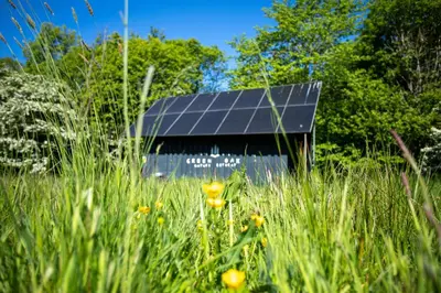 a barn with solar panels in a field of grass at Green Oak Nature Retreat in Dunfermline