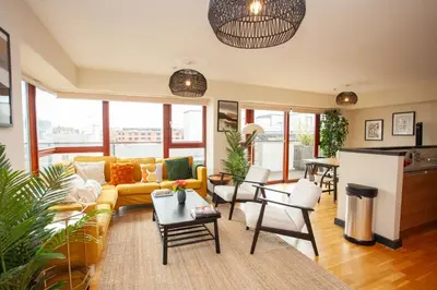 a living room with a yellow couch and chairs at Beautiful Penthouse in City Centre Location in Glasgow