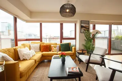 a living room with a yellow couch and a table at Beautiful Penthouse in City Centre Location in Glasgow