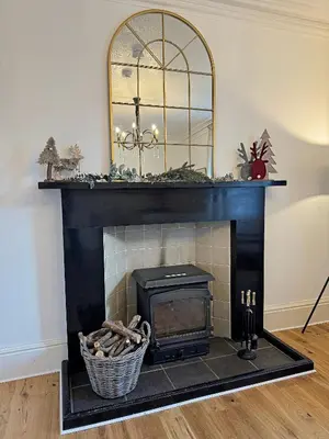 a fireplace with a mirror on top of it at Glenrigh House - beautiful garden with old church ruin in Onich