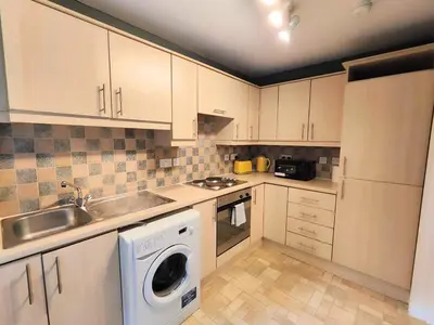 a kitchen with white cabinets and a washer at La Casita, Quarry - 2 bedroom Entire Apartment with Free Parking in Glasgow