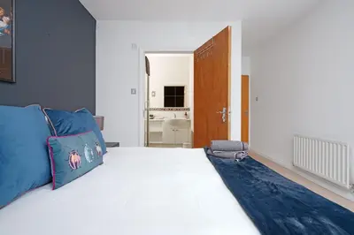 a bedroom with a large white bed with a blue blanket at 5 Bed Finnieston SkyHigh Duplex with Parking in Glasgow