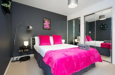 a bedroom with a large bed with a pink blanket at 5 Bed Finnieston SkyHigh Duplex with Parking in Glasgow