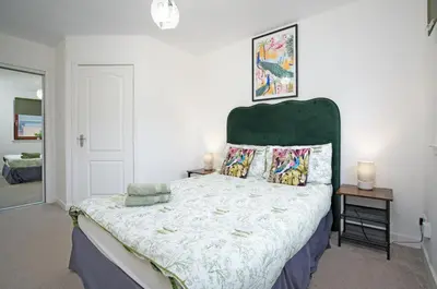 a bedroom with a large bed with a green headboard at 2Bed City Central East End Gem with Free Parking in Glasgow