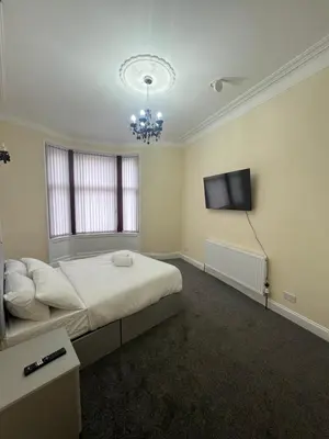 a bedroom with a bed and a flat screen tv at Glasgow South 2 Bedroom Apartment in Glasgow