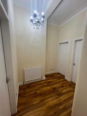 an empty room with a chandelier and wooden floors at Glasgow South 2 Bedroom Apartment in Glasgow